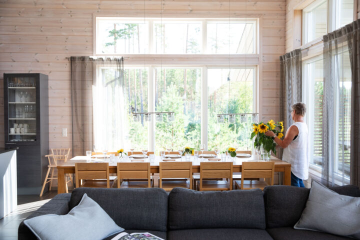Nainen laittaa kukkia pöydälle Tallusniemen huvilan ruokailutilassa