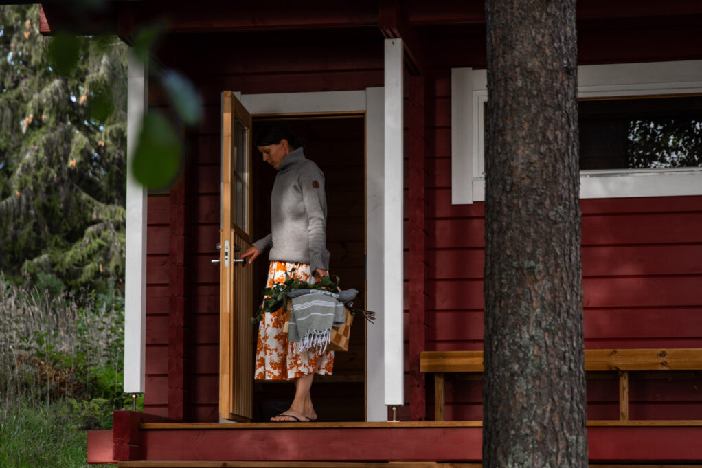 Woman standing on the terrace of a traditional wood heated log sauna
