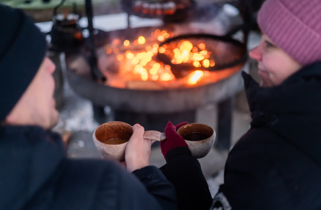 Two persons sitting by the outdoor fireplace and drinking coffee